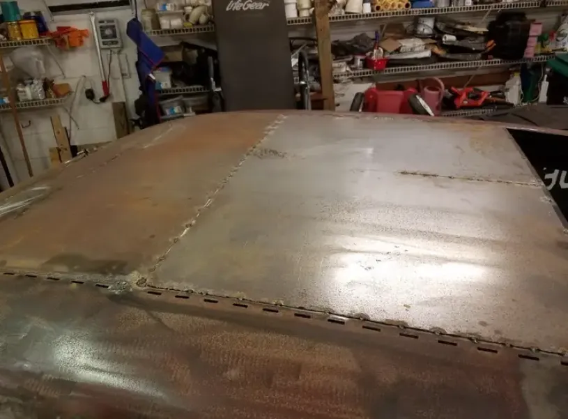 Warped, welded metal panels showing buckling and distortion in the garage workshop