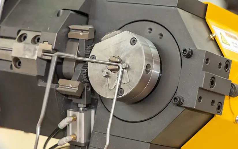 Wire forming machine with yellow cover and grey frame precisely bending and shaping wire